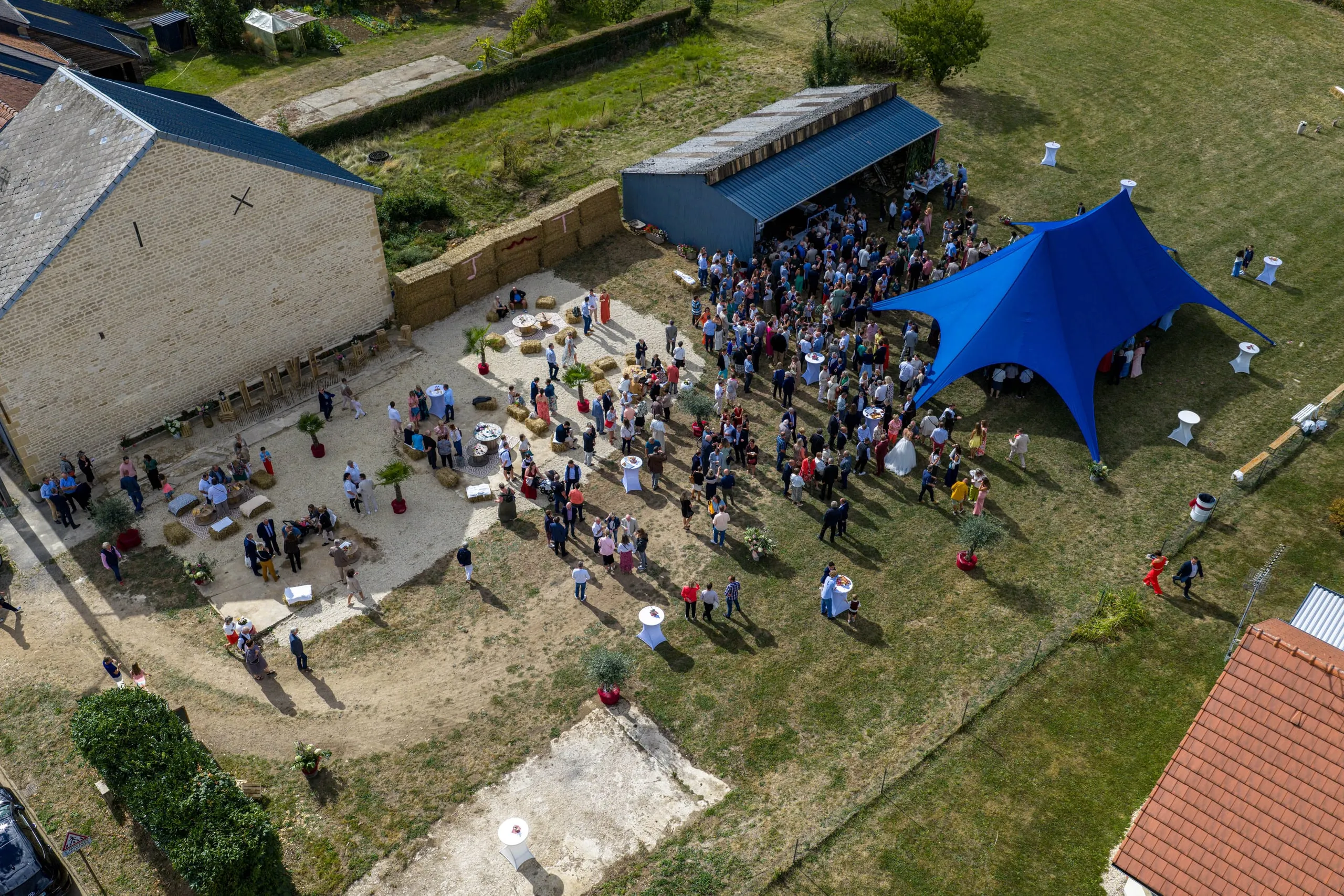 Vue aérienne d'un domaine de réception de mariage dans les Ardennes, tente étoilée et invités entre la grange et le jardin